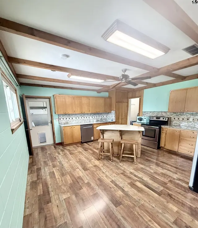 Spacious kitchen features wood-beamed ceiling, island with seating, and ample cabinetry.