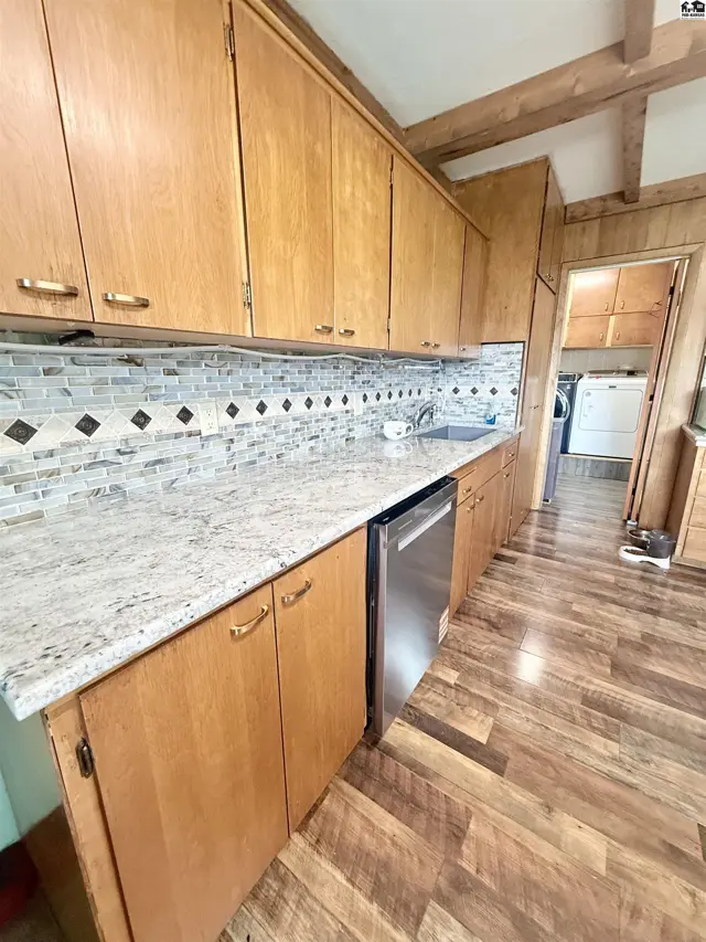 Kitchen features light wood cabinetry, granite countertops, and a mosaic tile backsplash.