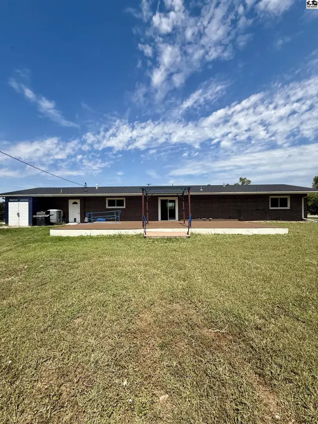 Spacious brick ranch home with a large wooden deck and expansive lawn.