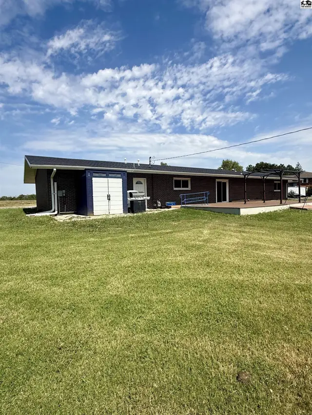 Brick home with a dark roof, white trim, and a large wooden deck.