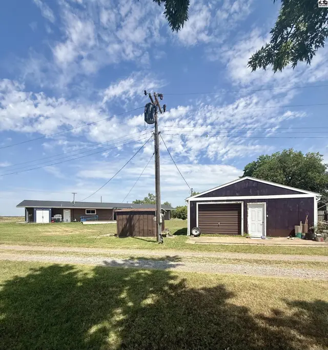 Two detached structures, one with a garage door, sit on a gravel driveway.