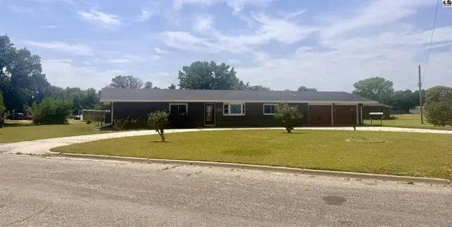 This single-story home features a dark exterior, a two-car garage, and a circular driveway.
