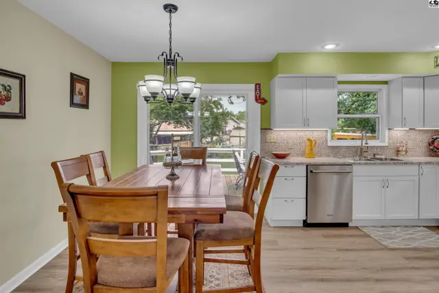 This dining area features a wooden table and chairs, with a modern kitchen visible.