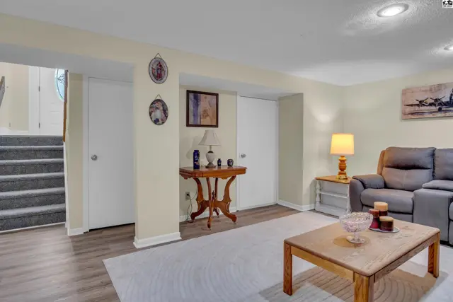 This finished basement features a carpeted staircase, wood-look flooring, and a comfortable seating area.