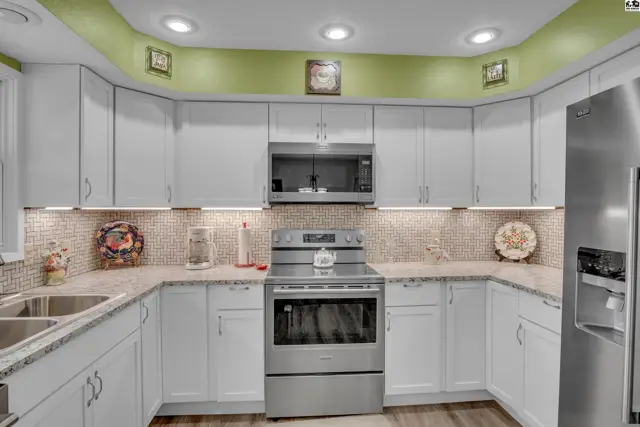 White cabinetry, stainless steel appliances, and granite countertops define this spacious kitchen.