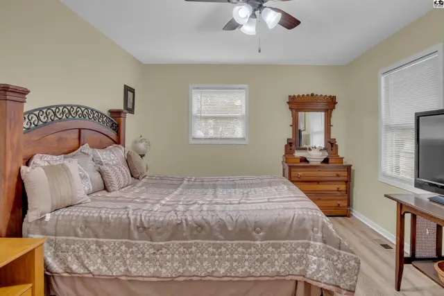 This bedroom features a king-size bed, a wooden dresser, and a ceiling fan.