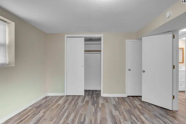 This room features wood-look flooring, neutral walls, and a closet with sliding doors.