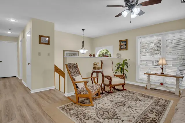 Living room features hardwood floors, a large area rug, and a ceiling fan.