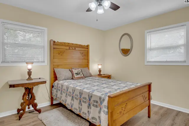 This bedroom features a wooden bed frame, two bedside tables, and a ceiling fan.
