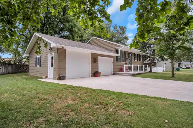 This tan-sided home features a two-car garage and a covered front porch.
