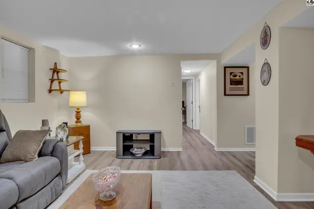 This finished basement features neutral walls, wood-look flooring, and recessed lighting.