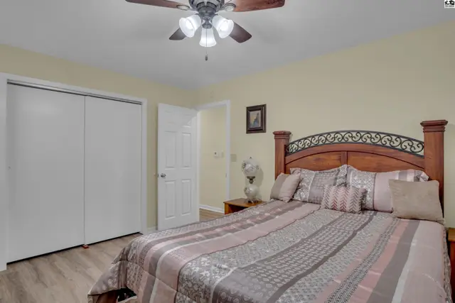 Spacious bedroom with a ceiling fan, large closet, and a wooden headboard.