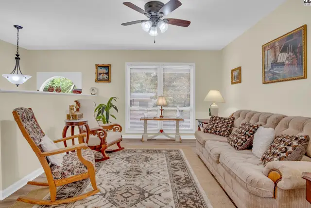 Spacious living room with neutral walls, a ceiling fan, and large windows.
