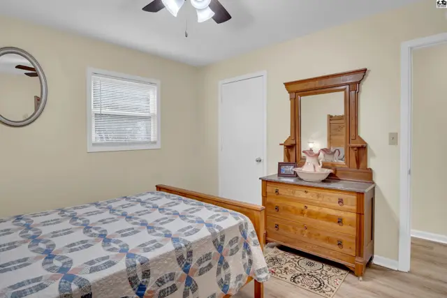 Bedroom with a wooden dresser, mirror, bed, and window.