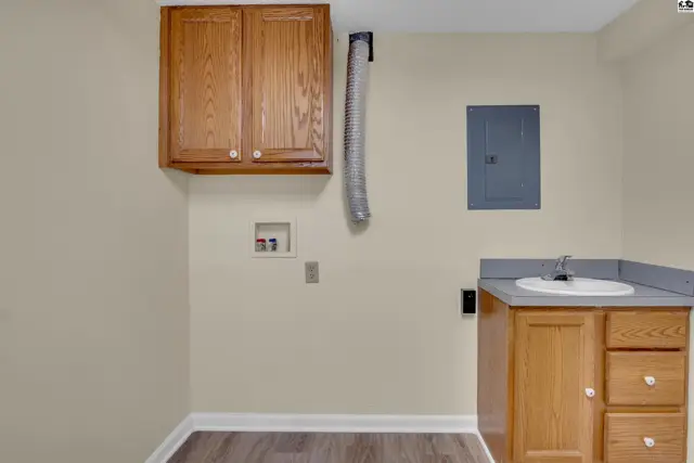 This room features wood cabinetry, a utility sink, and laundry hookups.