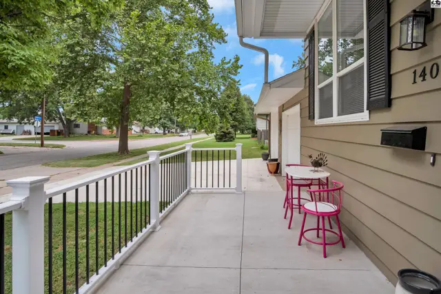 Covered porch with white railings and a small table with chairs.