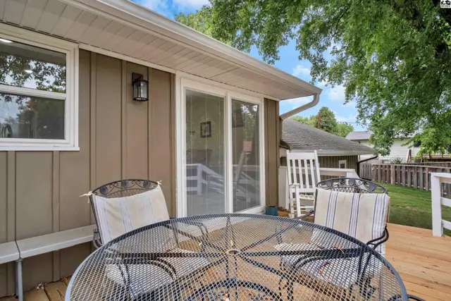A metal patio table and chairs sit on a wooden deck next to a sliding glass door.