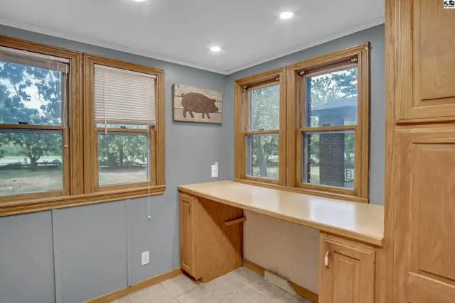 Built-in wooden desk and cabinetry complement the grey walls and tiled floor.