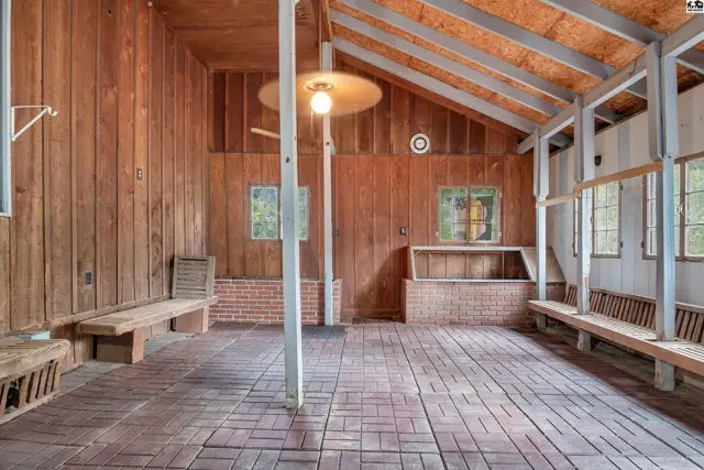 Wooden walls and ceiling with exposed beams frame a brick floor and built-in benches.