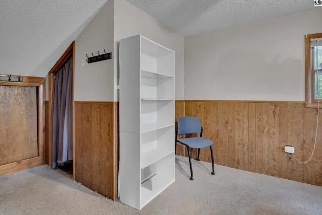 This room features wood-paneled walls, a white bookshelf, and a blue chair.