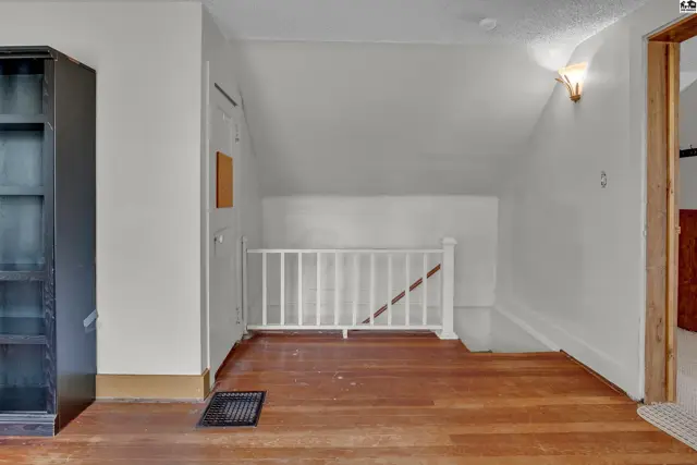 Wood floors and white railings accent this bright, airy landing with a built-in bookshelf.