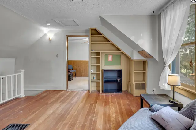 This room features hardwood floors, built-in shelving, and a large window.
