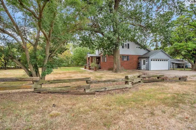 Brick and siding house with a two-car garage and covered carport sits on a grassy lot.