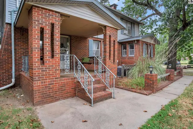 Brick home features a covered porch with steps and a concrete walkway.