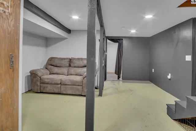 Finished basement with light green floor, gray walls, and a sofa.