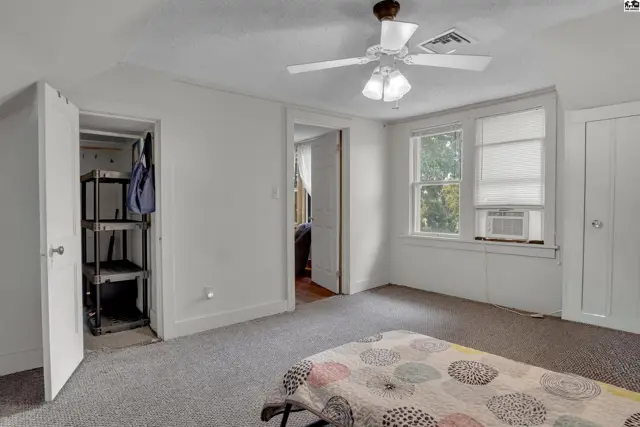This bedroom features a ceiling fan, closet with shelving, and two windows.