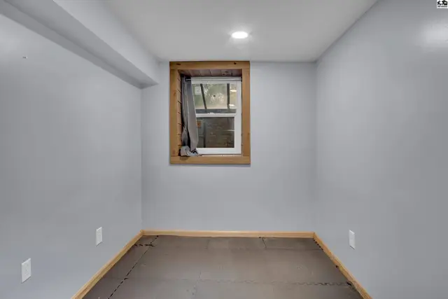 This room features light gray walls, a wood-trimmed window, and dark flooring.