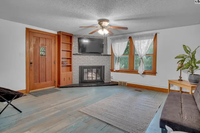 Living room features a brick fireplace, built-in shelving, and wood-paneled door.