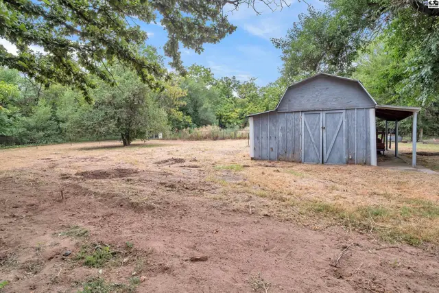 A weathered gray barn with double doors sits beside a covered lean-to.