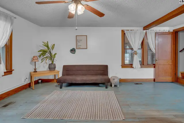 Living room features a futon, rug, and wooden floors with white walls.
