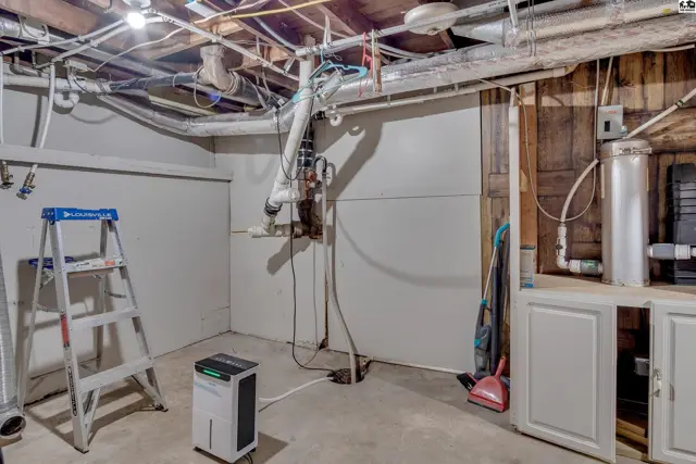 Concrete floor and unfinished walls with exposed pipes and a water heater.
