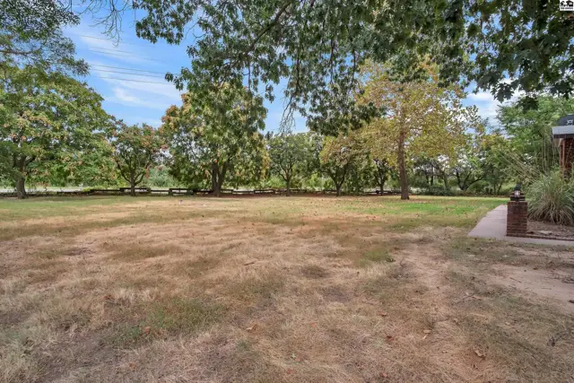 Spacious, level lot with mature trees and a paved walkway.
