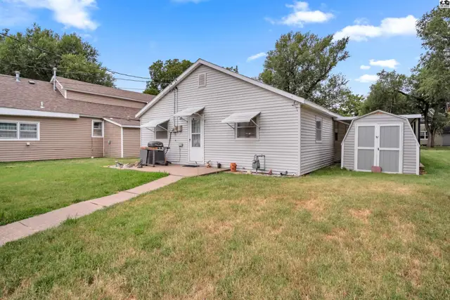 This home features a white vinyl-sided exterior with a detached storage shed and a grassy yard.