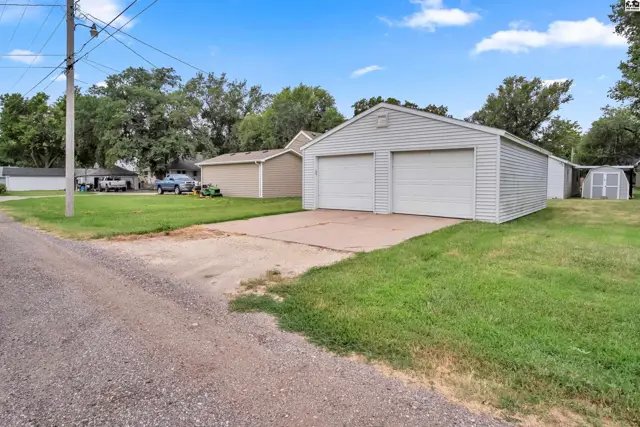 Two-car garage with white doors sits on a concrete pad with a small shed nearby.