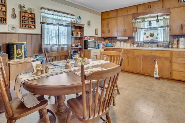 This kitchen features wood cabinetry, a dining table with chairs, and a built-in hutch.