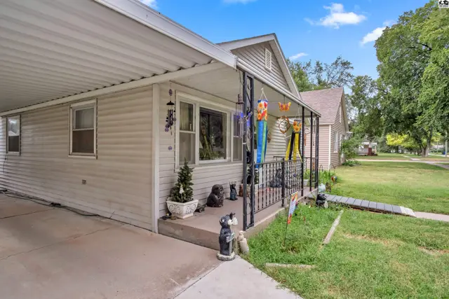 This home features a covered carport, a front porch with railing, and a grassy yard.