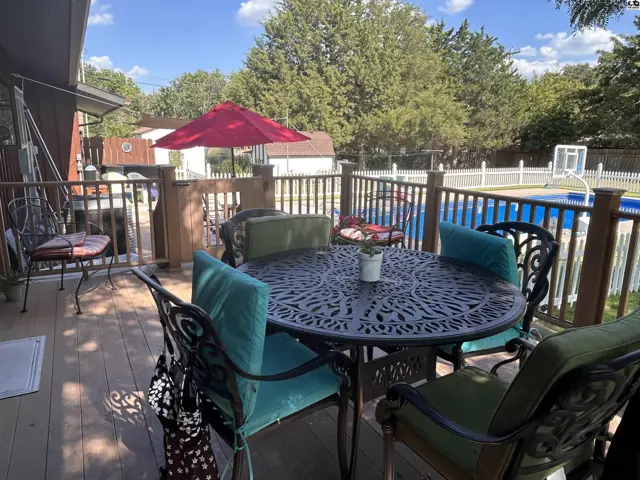 Deck with outdoor dining set, umbrella, and a fenced pool area.