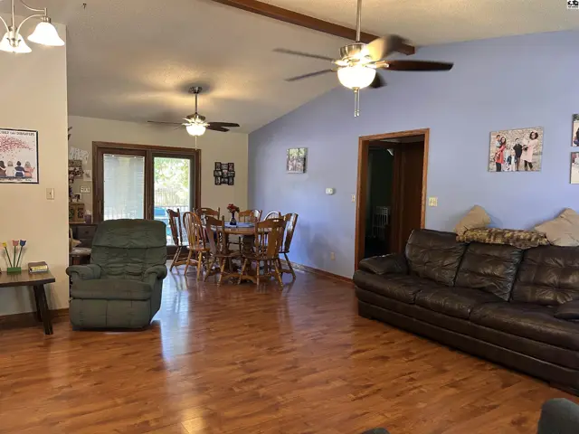 Spacious living and dining areas feature wood floors, vaulted ceilings, and ceiling fans.