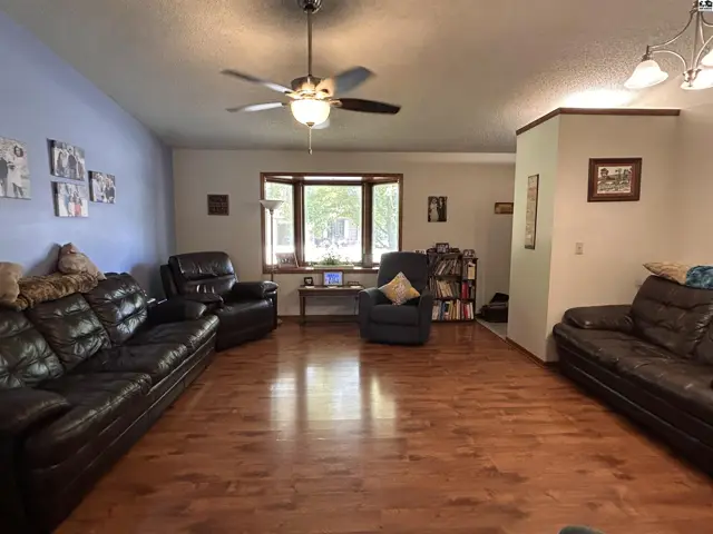 Spacious living room with hardwood floors, bay window, and ceiling fan.