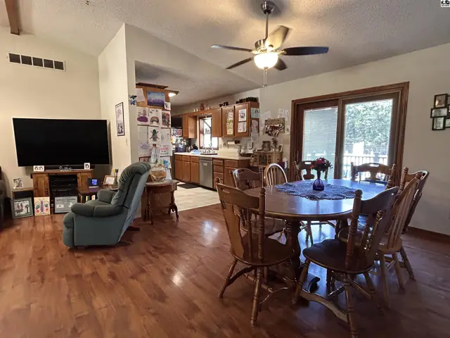 Spacious living area with hardwood floors, a dining table, and an adjacent kitchen.