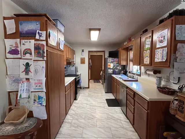 Spacious kitchen features wood cabinetry, white countertops, and a tiled floor.