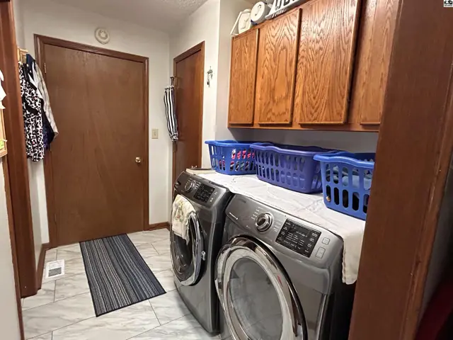 This laundry room features a washer, dryer, and ample wooden cabinetry.