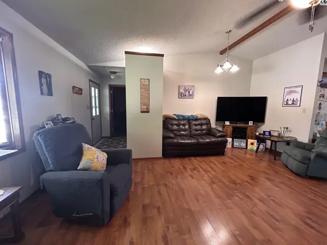 Spacious living room with hardwood floors, a television, and comfortable seating.