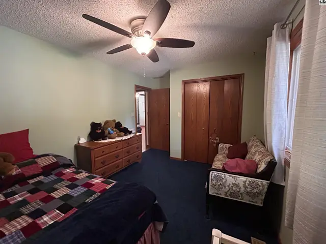 This bedroom features a vaulted ceiling, ceiling fan, and a closet with wooden doors.
