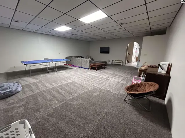 Spacious finished basement with carpeted floors, drop ceiling, and ample room for recreation.