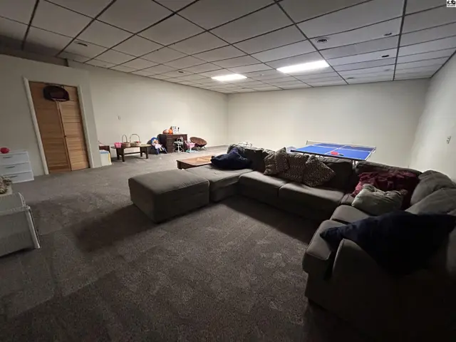 Spacious finished basement with carpet, sectional sofa, and ping pong table.